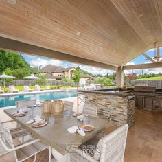 an outdoor kitchen and dining area next to a swimming pool