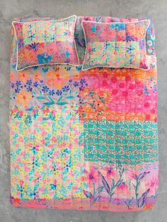 a colorful quilted bed with two pillows on top of it and one pillow in the middle