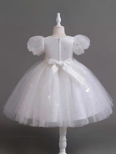 A touch of sweetness and a whole lot of elegance are in this beaded puff sleeve Communion dress. Designed to make special occasions even more magical with its glittering details and gorgeous beadwork, it's the ultimate twirl-worthy delight for your angel. Fluffy layers of lightweight fabric add a playful bounce to her moves, making each step extra charming. Sophisticated details elevate her look, ensuring a magical memory in the making. Perfect for Communion Day, weddings, pageants, birthday parties, dances, and other celebrations Puff sleeve tulle Communion dress with sequin details and beadwork waist accent Available in sizes 4T-12Y for toddlers and little girls Puff Sleeve Tulle Party Dress, Elegant Short Sleeve Princess Dress For Party, Embellished Glitter Tulle Princess Dress, Fitted Glitter Tulle Dress For Festive Occasions, Elegant Princess Dress For Christmas Baptism, White Short Sleeve Princess Dress For Party, Princess Style Puff Sleeve Dress For Party, White Tulle Christmas Dress, Elegant Short Sleeve Princess Dress For Dress-up