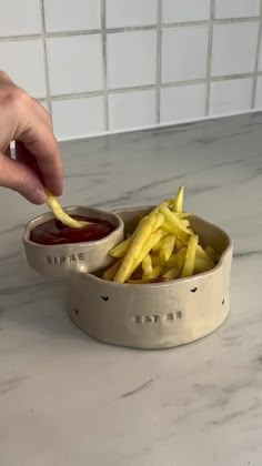 a person dipping fries into a bowl with ketchup