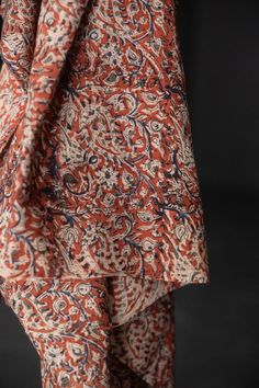 an orange and blue paisley print dress is shown from the waist up, with black background