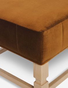 the footstool is made out of wood and has a brown velvet upholstered