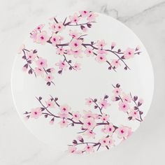 a white plate with pink flowers on it sitting on a marble countertop next to a knife and fork