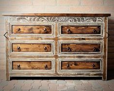 an old wooden dresser with many drawers and knobs on the top, sitting in front of a brick wall