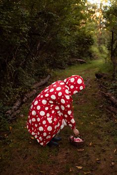 a woman in red and white polka dot dress crouching down to pick up her shoes