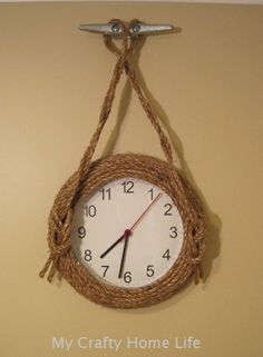 a clock hanging from the side of a wall with rope on it's sides