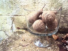 three balls of yarn are in a glass bowl on the ground next to a wall