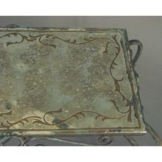 an old metal tray with ornate designs on the top and bottom, sitting on a table