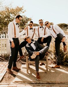 a group of men in suits and bow ties posing for a photo on a bench