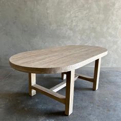 a wooden table sitting on top of a cement floor next to a gray concrete wall