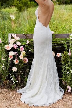 a woman in a white wedding dress standing on a bench with her back to the camera