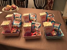 several boxes of popcorn sitting on top of a table next to a bowl of fruit