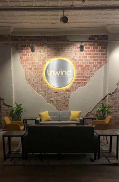 a living room with couches and tables in front of a sign that reads unwind