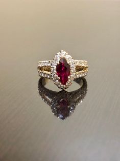 "DeKara Designs Collection Metal- 18K Yellow Gold, .750. Stones- Marquise Ruby Center Beautiful Red Color 1.07 Carats. 16 Round Diamonds F-G Color VS2 Clarity, 1.15 Carats. This is a halo setting with a magnificent marquise ruby set in the center surrounded by 48 round diamonds in a \"U\" pave setting, and features a split shank. The marquise ruby is 1.07 carat with an beautiful hue of red in color. Rubies are the rarest of fine gemstone! The side stones are all F-G in color and VS2-SI1 in clari Elegant Marquise Ruby Ring With Vvs Clarity, Luxury Ruby Marquise Cut Rings, Marquise Ruby Rings With Brilliant Cut, Fine Jewelry Marquise Ruby Ring With Halo Setting, Marquise Ruby Ring With Halo Setting, Dazzling Marquise Diamond Ring With Gemstone, Fine Jewelry Ruby Ring With Marquise Halo, Red Marquise Brilliant Cut Ring, Luxury Marquise Cut Yellow Gold Ruby Ring