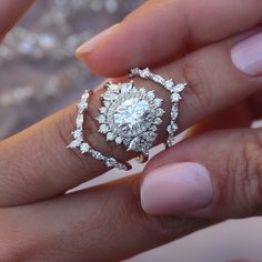 a woman's hand holding an engagement ring with diamonds on the top and bottom