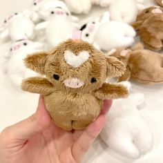 a person holding a small stuffed animal in front of many other stuffed animals on a table