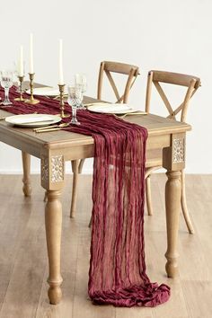 the table is set with two chairs and a red scarf draped over it's placemat