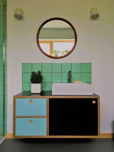 a bathroom with a sink, mirror and green tiles on the wall in it's corner