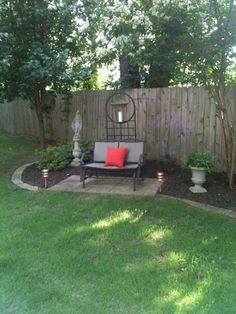 a bench sitting in the middle of a yard next to a wooden fence and trees