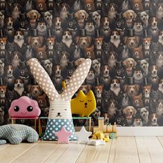 two stuffed animals sitting on top of a wooden floor next to a wall with dogs