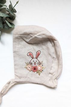 Adorn your little one with this exquisite handmade baby bonnet hat, crafted from premium linen fabric and featuring delicate garden embroidery. Each bonnet showcases an enchanting bunny with flowers, meticulously stitched to perfection.  The inside material is made of soft, breathable muslin, ensuring comfort and gentle protection for your baby's sensitive skin. Perfect for special occasions, photo shoots, or everyday elegance, this bonnet is a beautiful blend of style and quality craftsmanship. Bunny With Flowers, Garden Embroidery, Bunny Embroidery, Everyday Elegance, Bonnet Hat, Baby Bonnet, Skull Cap Beanie, Handmade Baby, Linen Fabric