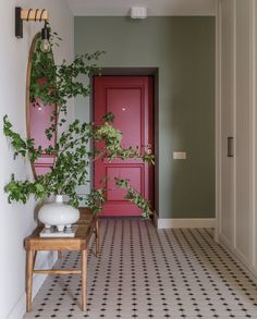 an entryway with a red door and potted plant next to the entrance table