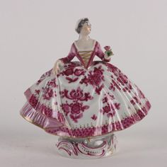 a porcelain figurine in the shape of a woman wearing a pink and white dress