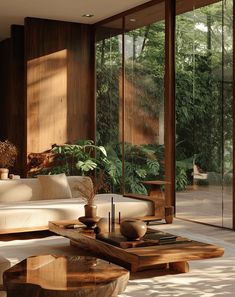 a living room filled with furniture and lots of windows covered in glass doors that look out onto the woods