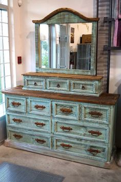 an old dresser with drawers and a mirror on it's top, in front of a window