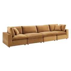 a large sectional couch with pillows on the top and bottom ends, in tan color