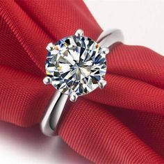 a diamond ring sitting on top of a red cloth