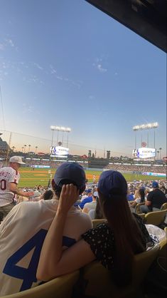 two people sitting in the stands at a baseball game, one is covering his face