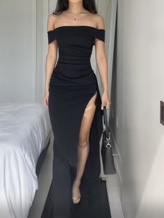 a woman in a black dress is posing for the camera with her legs slited