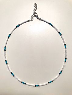 This dainty Seed Bead Choker Necklace is made with pretty WHITE glass seed beads. There is a hint of turquoise seed beads that create a stripe style pattern. The tiny seed beads are strung on beading wire & finished with a silver plated lobster style clasp with a 2 inch extension chain, to allow for personal size adjustments. These necklaces are perfect for everyday wear. Enjoy a simple, boho /chic look with a single strand or layer them with some of our other chokers. * Custom hand-made to Seed Bead Necklace Choker, Glass Seed Bead Necklace, The Tiny Seed, Seed Bead Choker, Bead Choker Necklace, Beaded Necklace Patterns, Necklace Patterns, Beading Wire, Beaded Choker Necklace