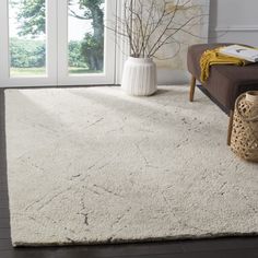 a living room with a white rug on the floor next to a couch and window