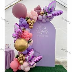 a balloon arch with balloons and butterflies on it