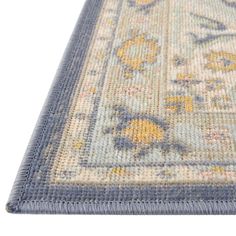 an area rug with blue and yellow flowers on the bottom, in front of a white background