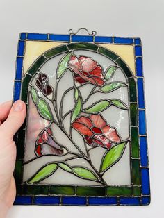 a hand holding a stained glass piece with flowers on it