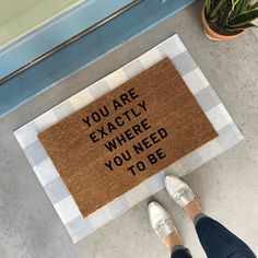 a person standing in front of a door mat that says you are exactly where you need to be