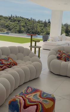 a living room filled with white furniture next to a large open area covered in trees