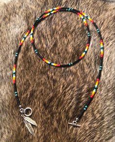 a necklace with beads and charms on top of a cowhide rug, next to a cell phone