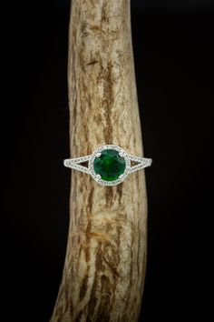 Product Details Ring Style:The "Aura" is a birthstone ring with a split shank-style & lab-created emerald women's ring with delicate and ornate details and is available with many center stone options Center Stone:7mm Round Lab-createdEmerald Materials: 14K gold engagement ring featuring a lab-created emerald center stone and a 1/5 ctw diamond halo and accents. Customizable:Because each of our rings is handcrafted to order, wecan customize yours using unique materials, gemstones, or design fe Halo Promise Ring With May Birthstone, May Birthstone Halo Ring For Promise, Green Emerald Jewelry With Halo Detail, Green Emerald Halo Jewelry, Heirloom Green Halo Jewelry, Heirloom Style May Birthstone Jewelry For Promise, Halo Setting Jewelry With Round Stone For May Birthstone, Halo Diamond Ring For May Birthstone, Emerald Ring With Halo Design For May Birthstone