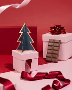 two white boxes with red ribbon and a christmas tree on top, one is empty