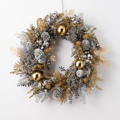 a silver and gold christmas wreath hanging on the wall