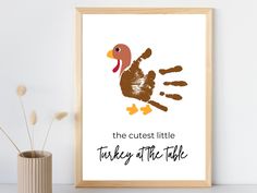 a framed poster with a handprint of a turkey and the words, the cutest little turkey at the table