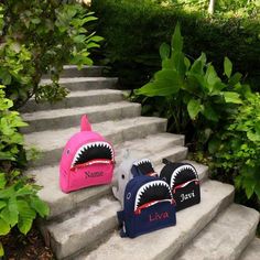 three personalized shark backpacks sitting on the steps in front of some bushes and trees