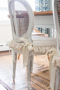 a white chair with a bow on the back of it's seat, sitting in front of a dining room table