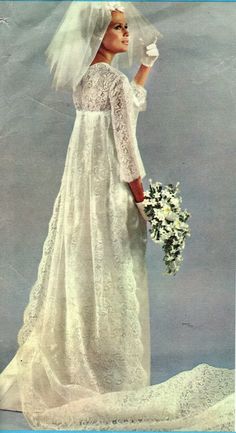 a woman in a white wedding dress and veil holding a flower bouquet with her right hand