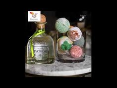 two glass bottles filled with different flavored donuts on top of a marble table