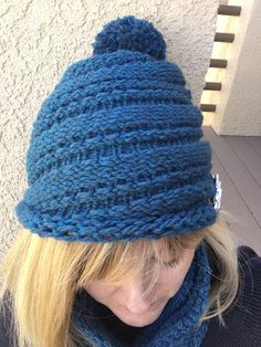 a woman with blonde hair wearing a blue knitted hat, scarf and neckwarf